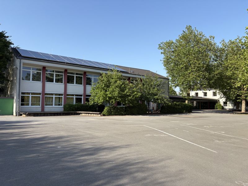 Die GGS Millrath an einem sonnigen Tag, Schulgebäude mit Schulhof